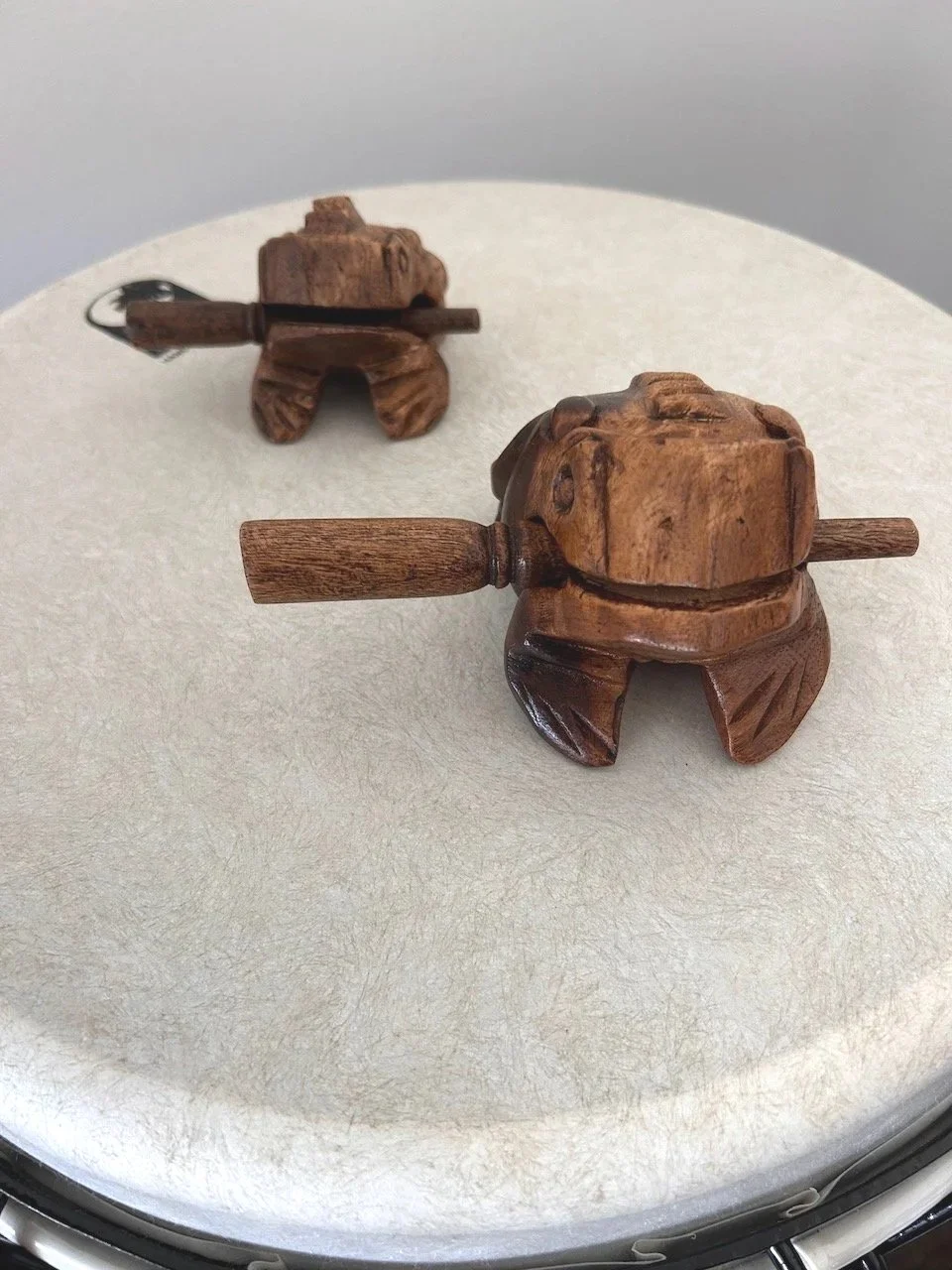 Wooden frog-shaped percussion instruments resting on a hand drum.