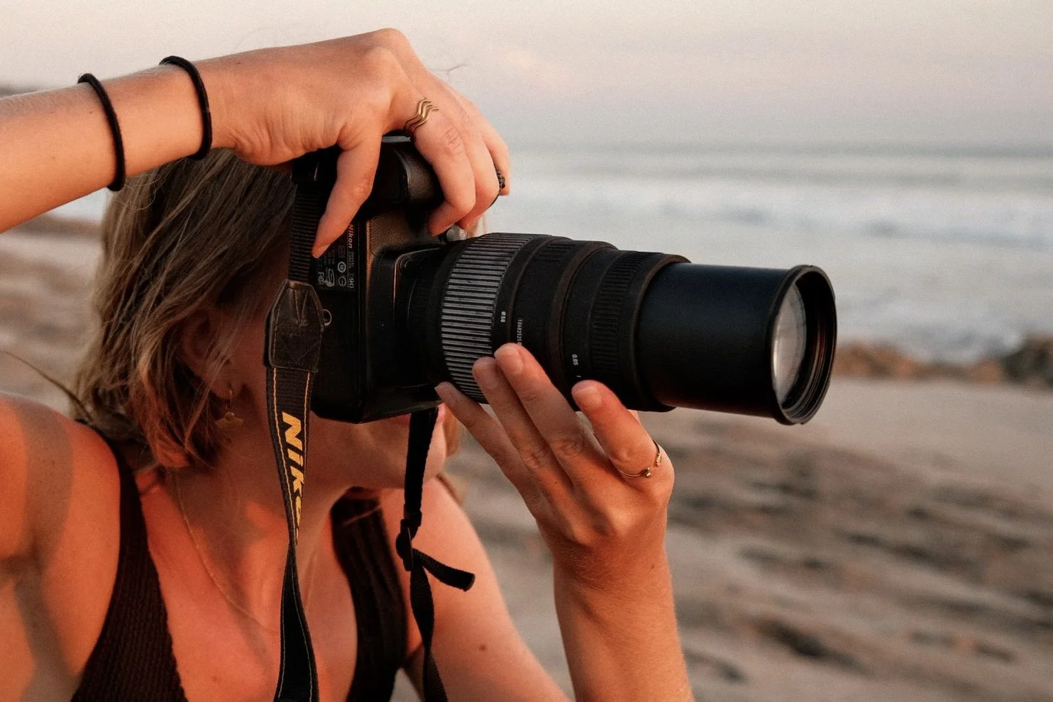 Person taking a photograph with a camera on a beach.