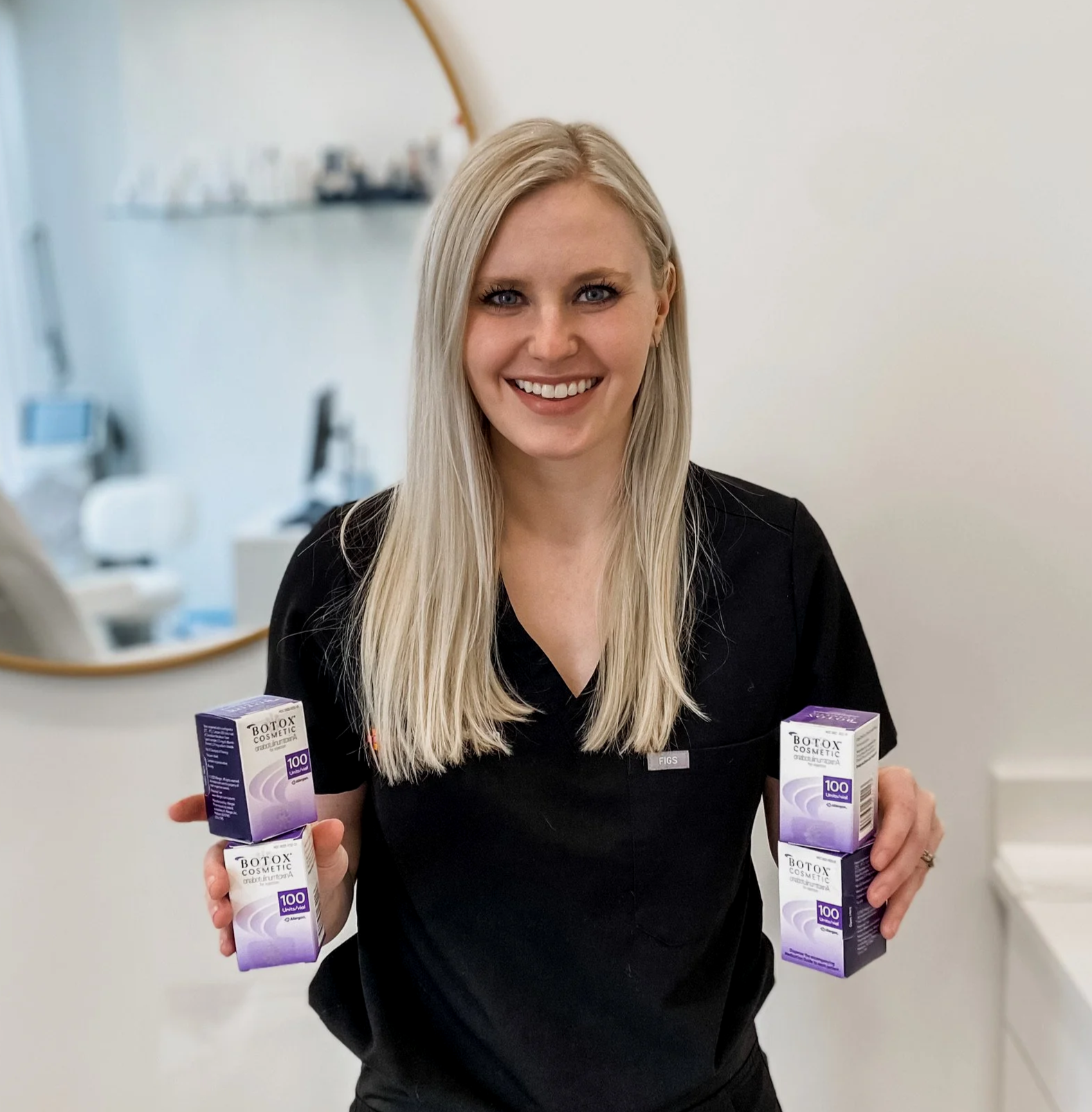 A smiling woman with blonde hair is holding four boxes of Botox Cosmetic, two in each hand.