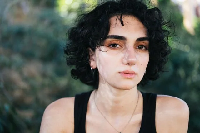 A woman looking right at you with black curly hair