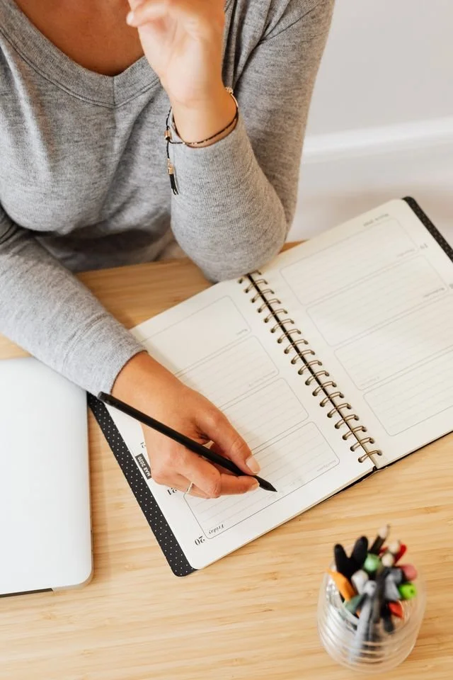a close up of a woman writing in a notebook