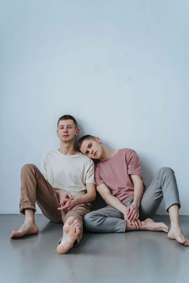 two LGBTQ guys sitting by a wall