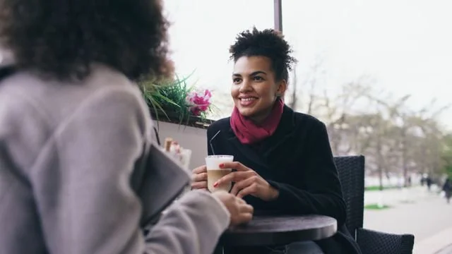 Two friends having coffee smiling