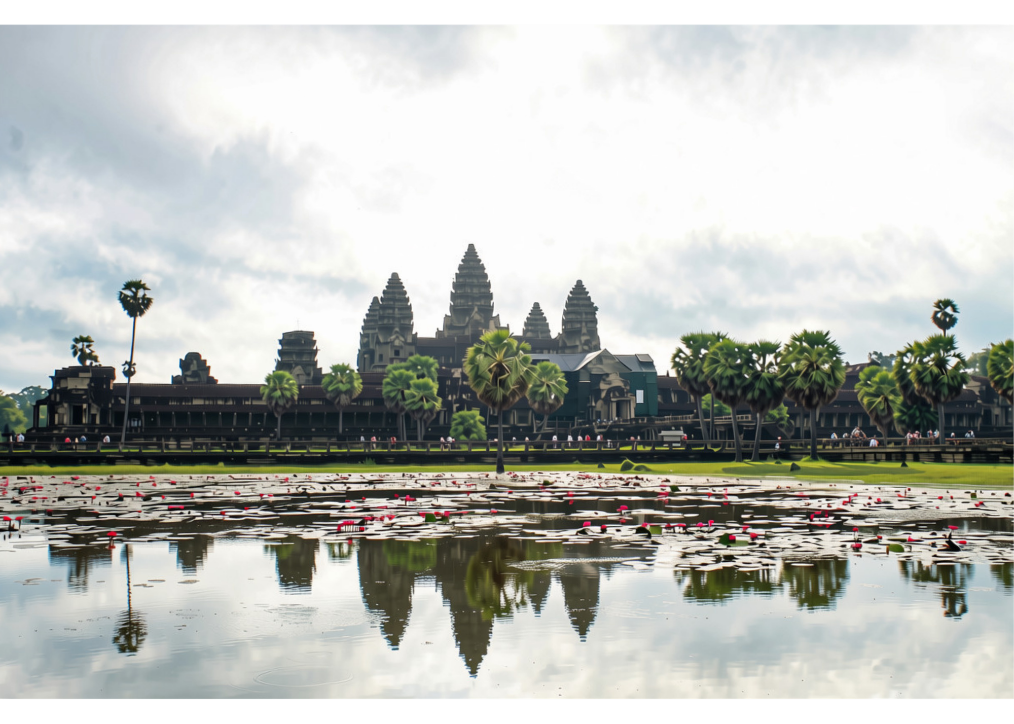 View of Angkor Wat temple in Cambodia, with a pond in the foreground reflecting the structure and sky, surrounded by lush greenery.