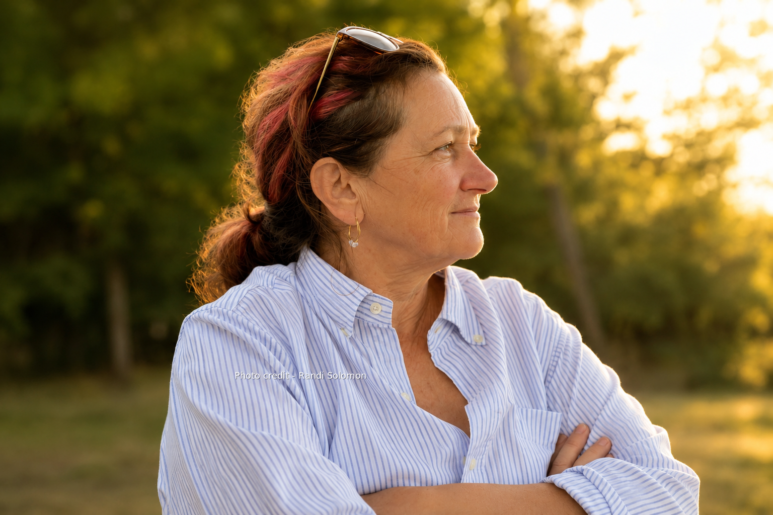 Janet Williams in profile outdoors at golden hour, wearing a blue-and-white striped shirt.