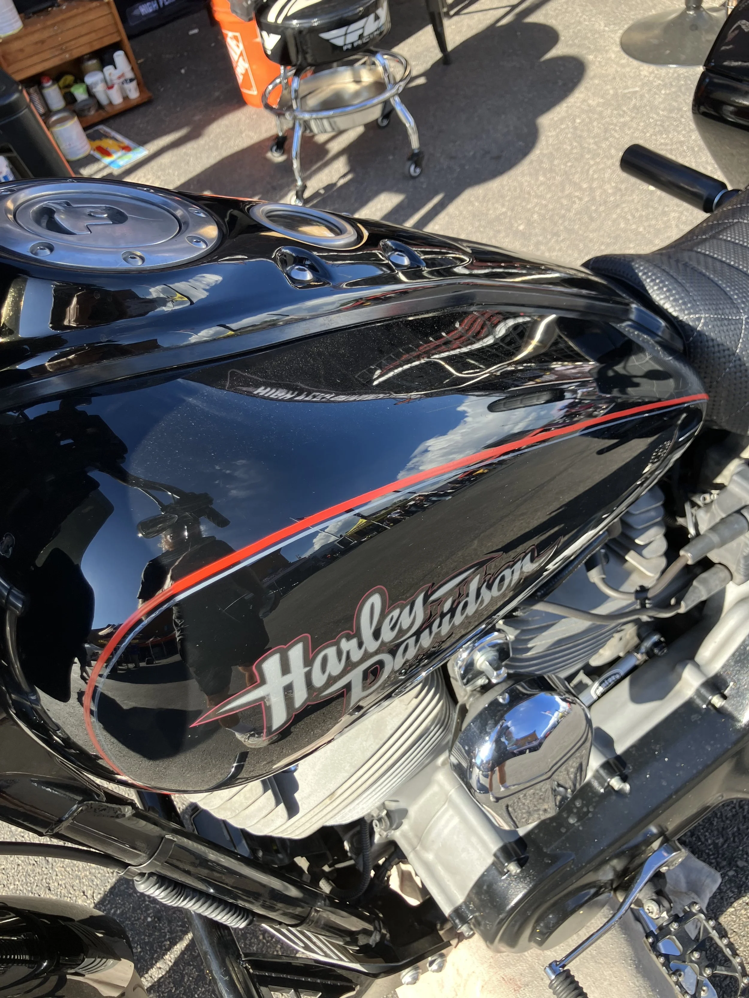 Close-up of a black Harley-Davidson motorcycle with a red stripe and chrome details, parked on a pavement.