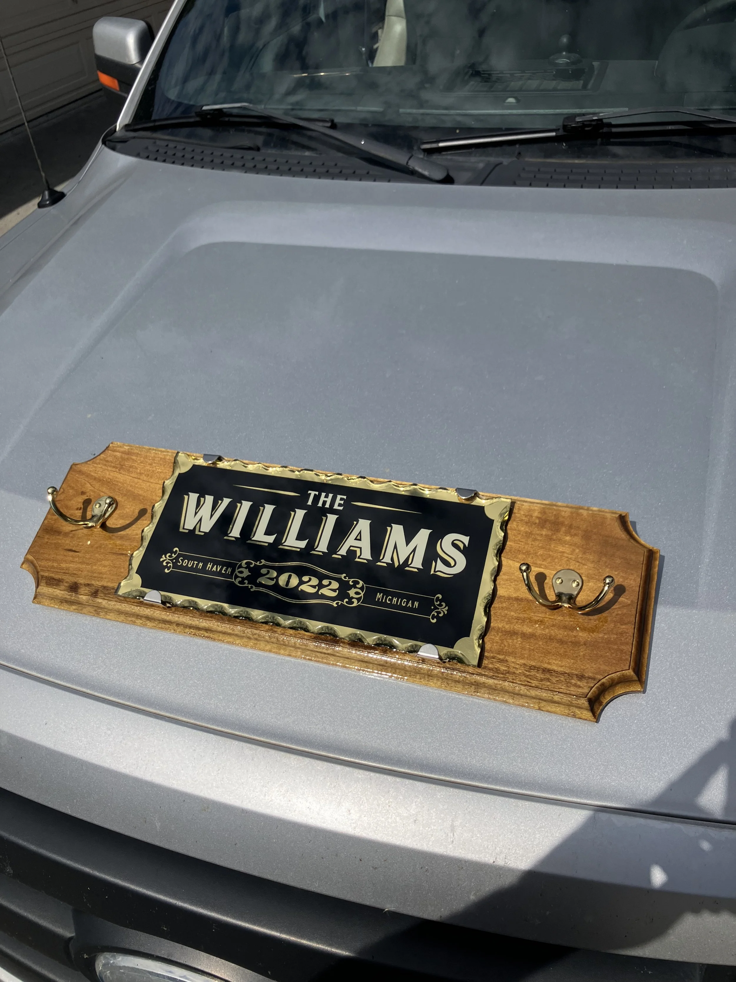 Car with a wooden plaque on the hood that reads ''The Williams South Haven Michigan 2022''.