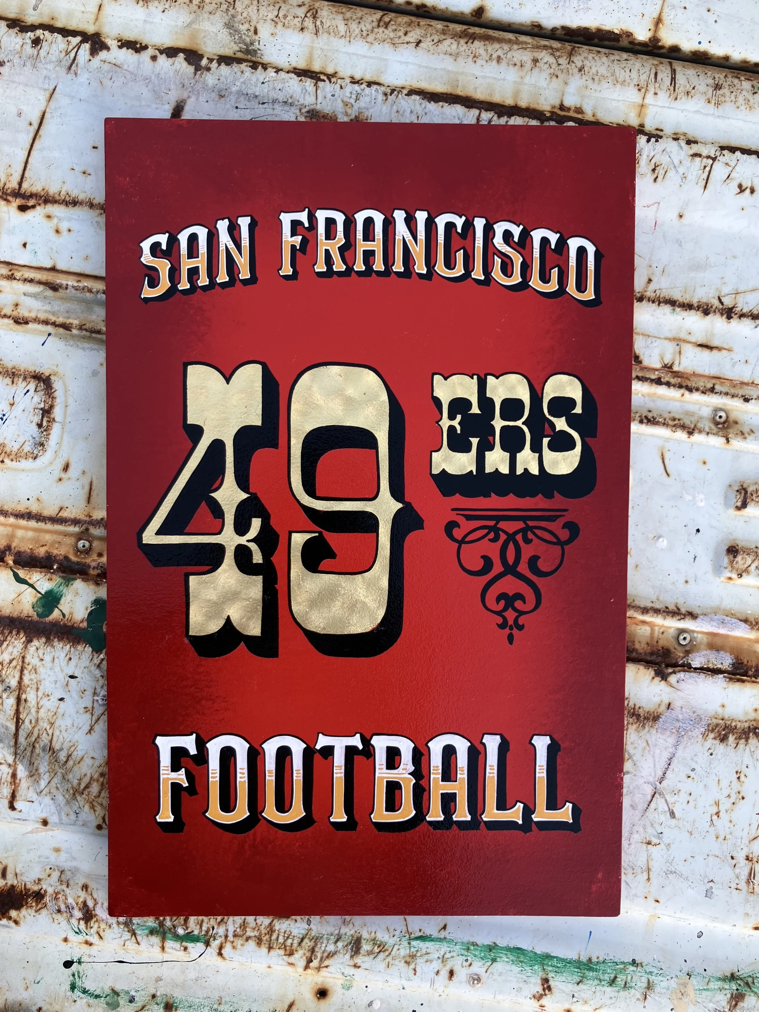A poster displaying the words "San Francisco" at the top, with the large numbers "49" and the words "FOOTBALL" below, on a rusty, weathered white surface.