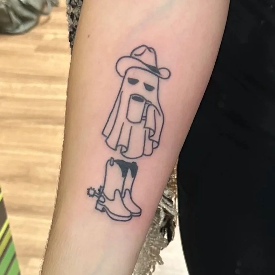 A line art tattoo of a ghost wearing a cowboy hat, with a dopey expression, boots, and holding a mug.
