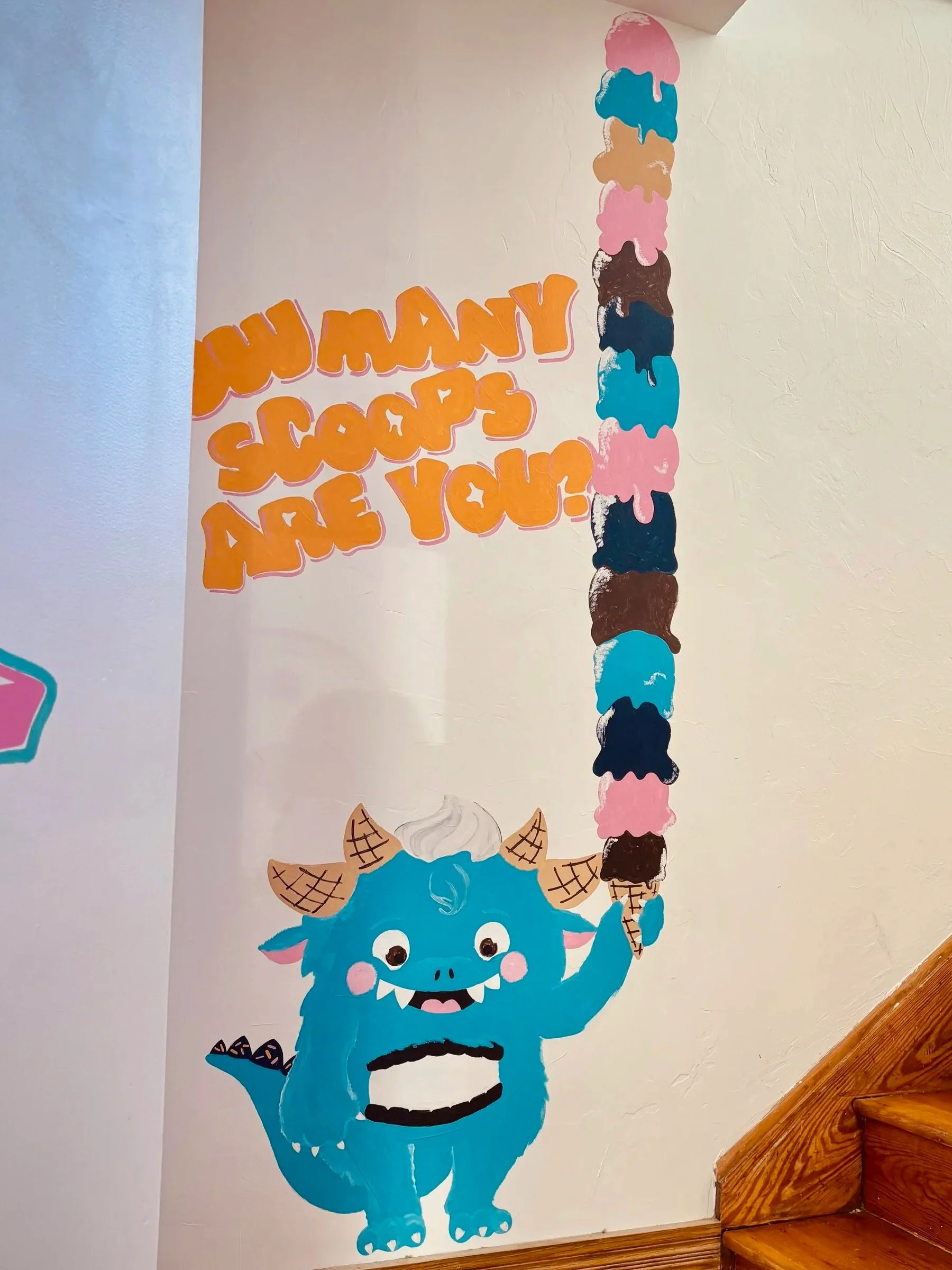 Colorful mural of a blue Winona Monster with ice cream cones stacked on a cone, accompanied by the text 'How may scoops are you?' in orange letters with pink outline.