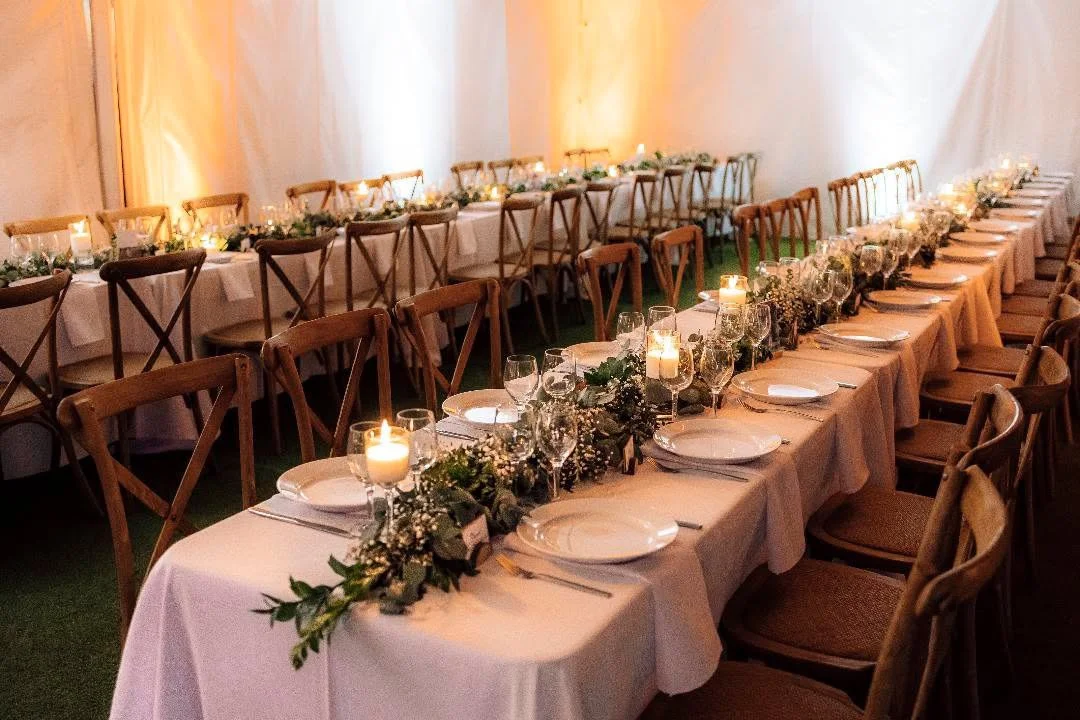 Table de banquet décorée avec des bougies, des fleurs et des assiettes, dans une ambiance chaleureuse.