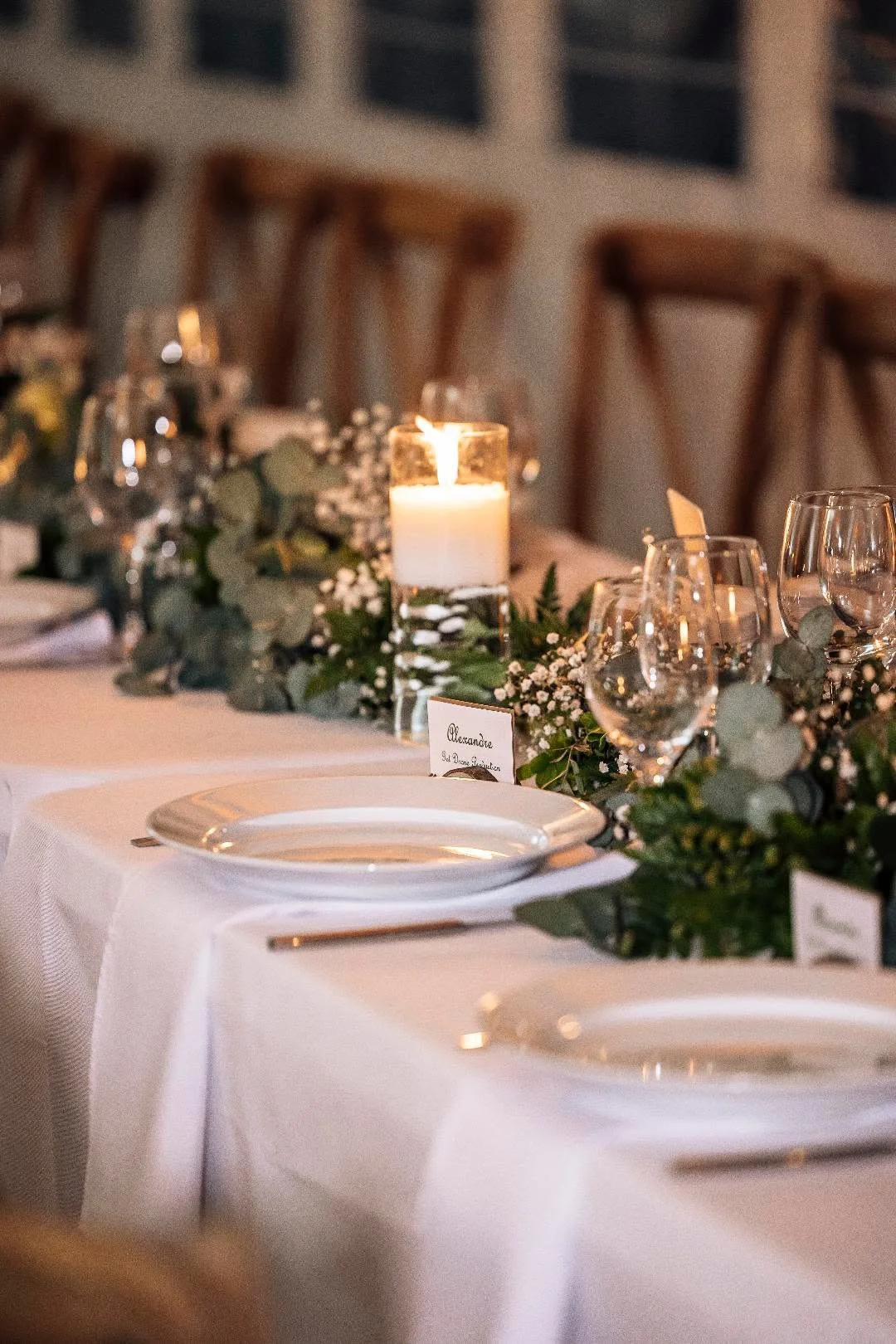 Table élégamment dressée avec des assiettes, des verres, des bougies et une décoration florale, pour un événement ou un dîner formel.
