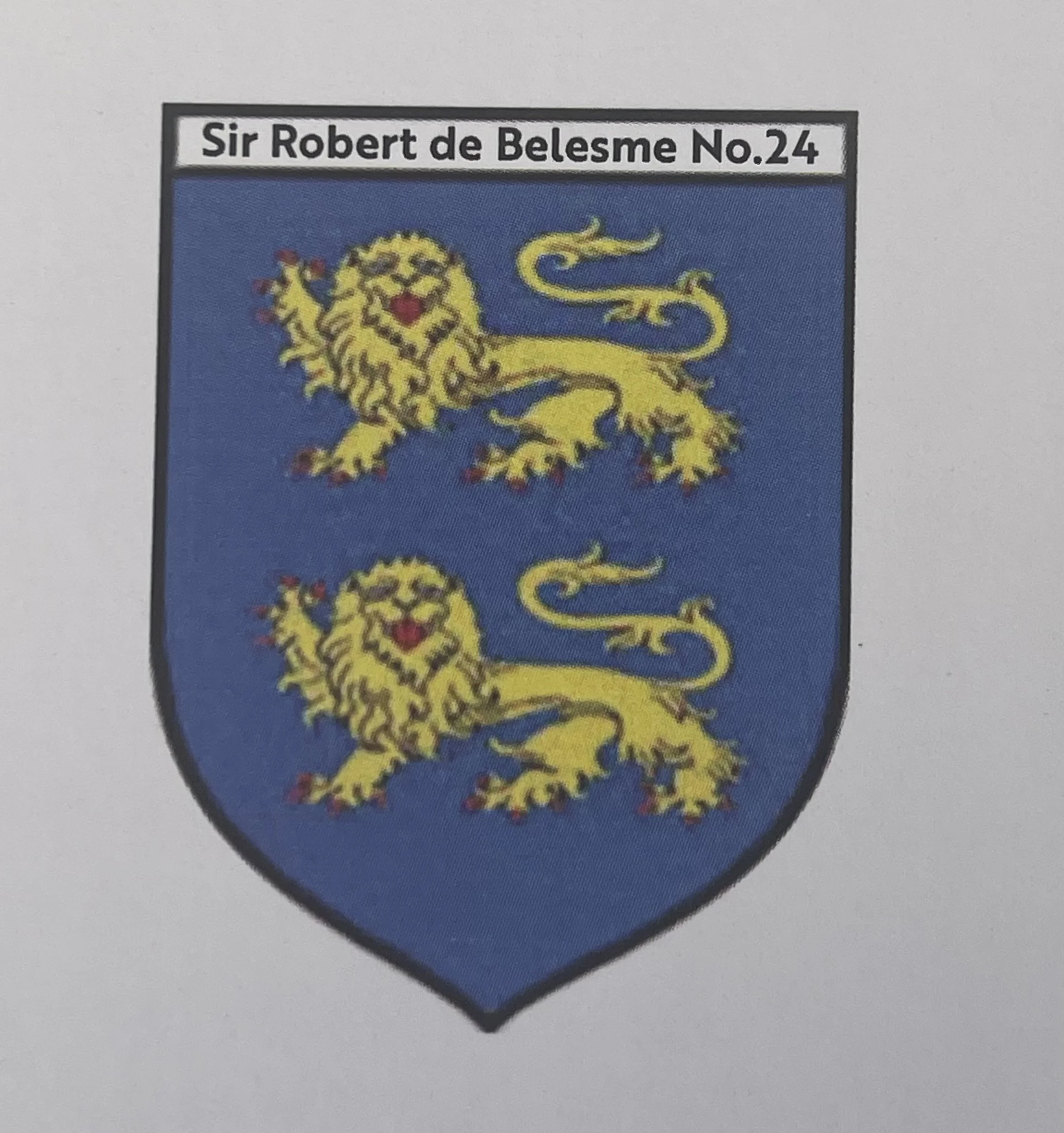 A coat of arms shield featuring a blue background with a golden lion rampant, top banner displaying the name 'Sir Robert de Belesme No.24'.