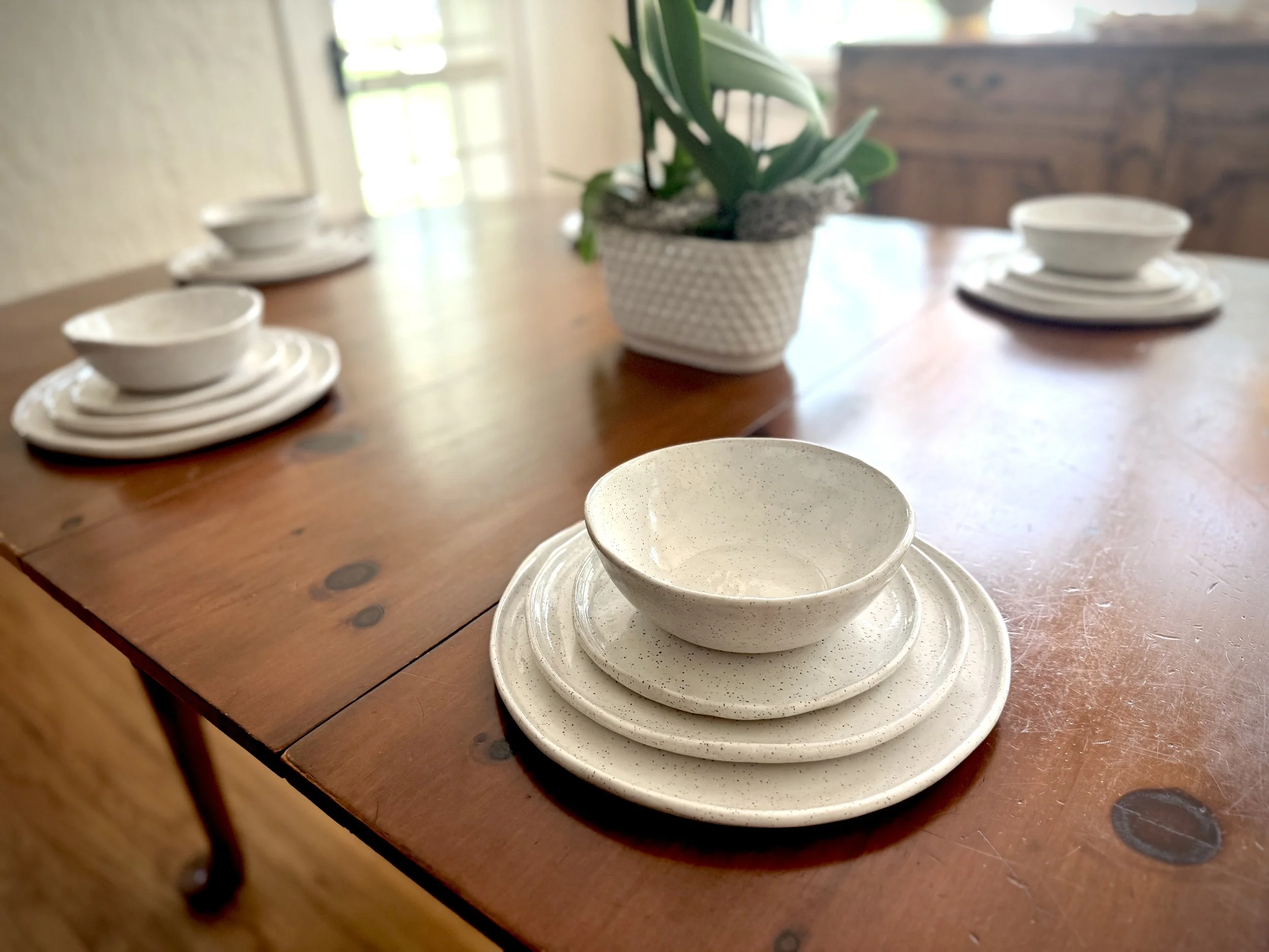 Four piece place setting.  White porcelain dinner plate, salad plate, bread plate and soup bowl.