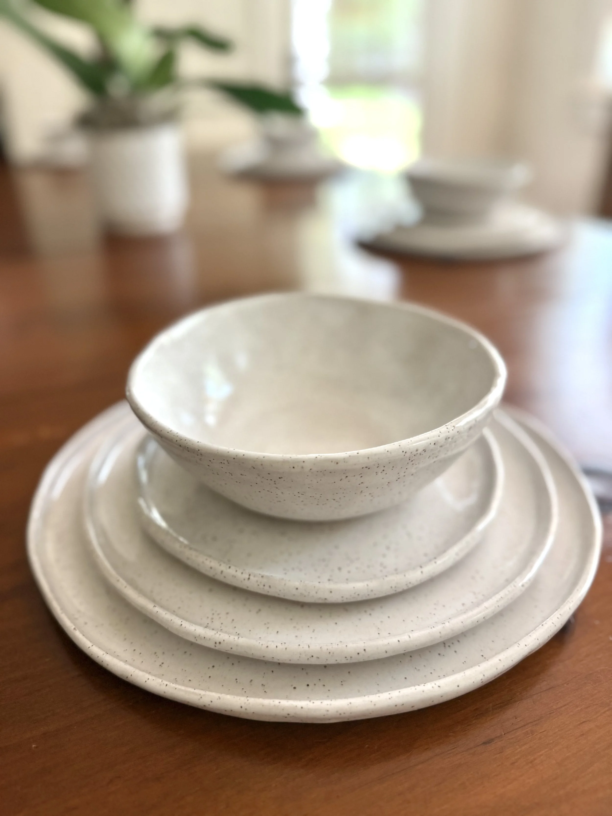 Four piece place setting.  White porcelain dinner plate, salad plate, bread plate and soup bowl.
