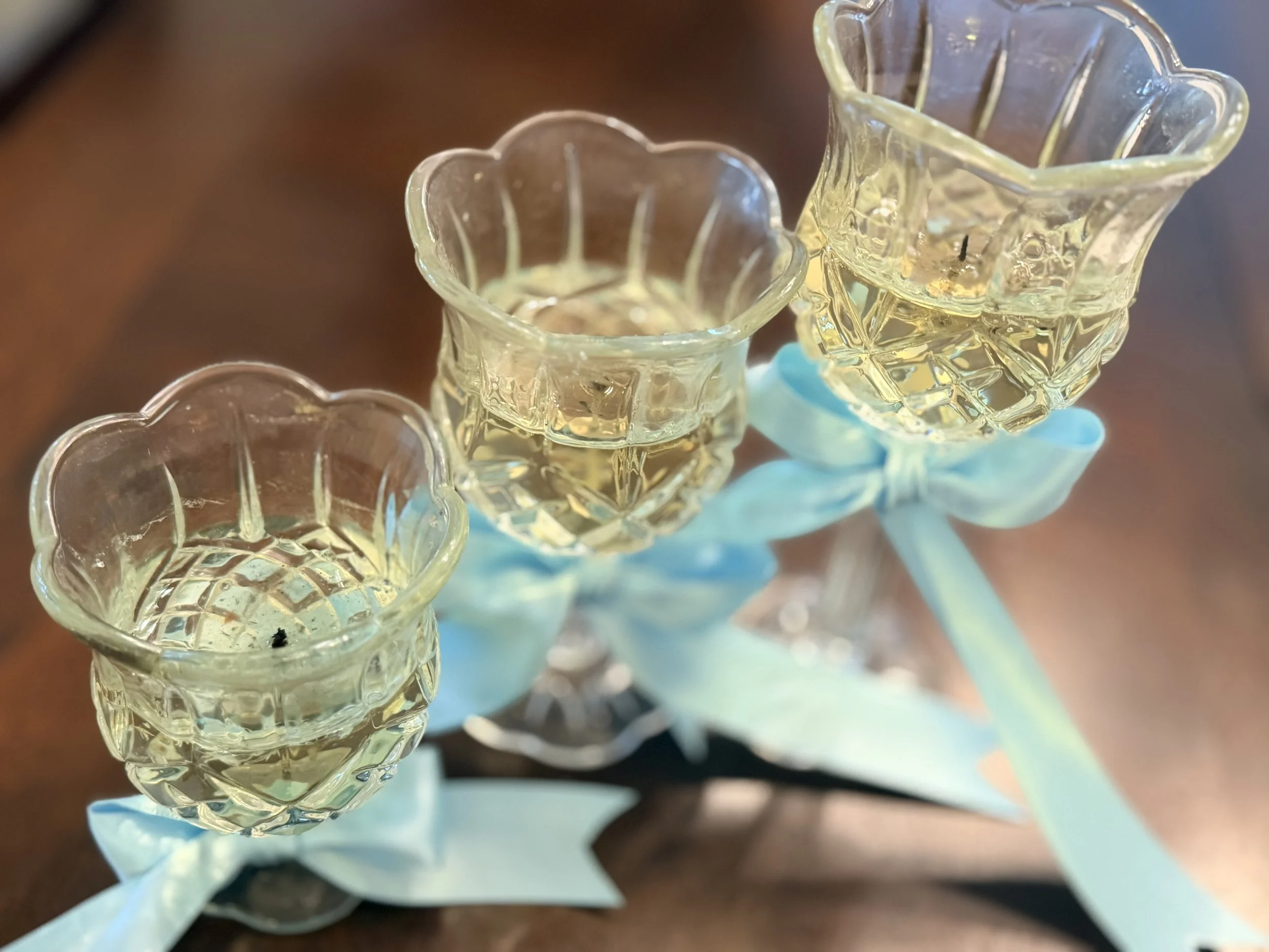 Close-up of small, clear glass flower-shaped vases filled with water, held together with a light blue ribbon.