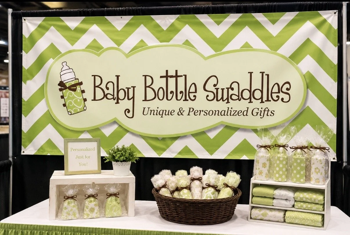 Display of personalized baby bottle gifts including wrapped bottles in a basket and on shelves, with a sign that reads 'Personalized Just for You!' at a baby bottle shop.