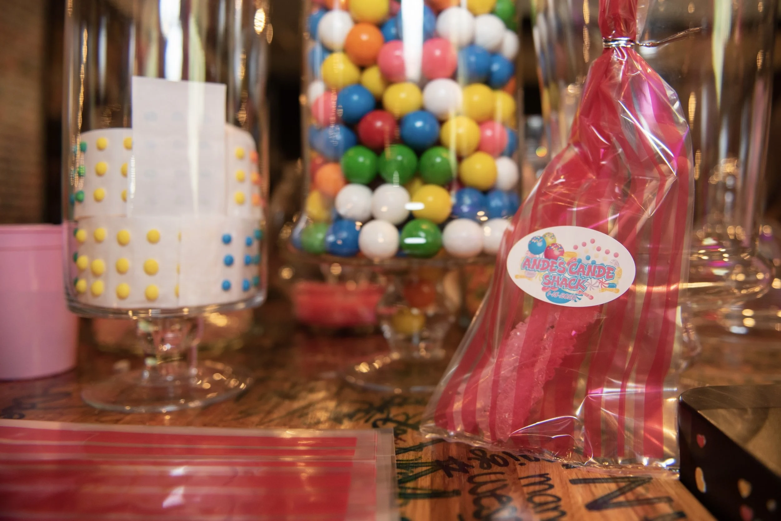 Colorful gumballs in a glass container and a pink bag of candy from Andes Cande Shack.