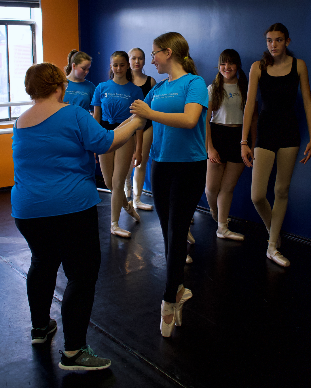 Ballet instructor giving instructions to students before a ballet class in a dance studio.