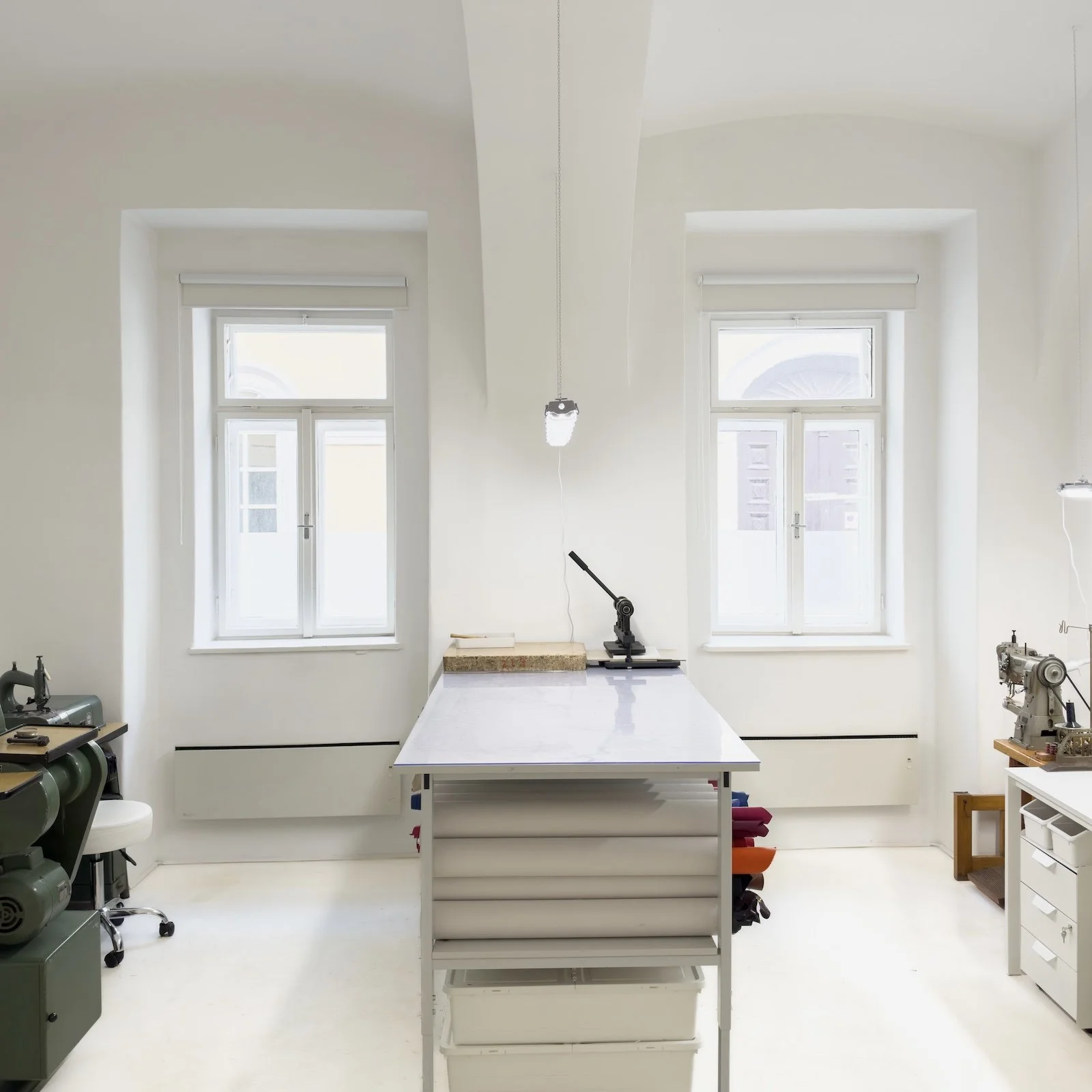 Blick in die Lederwerkstatt mit einem großen Arbeitstisch und professionellen Maschinen zur Lederverarbeitung.