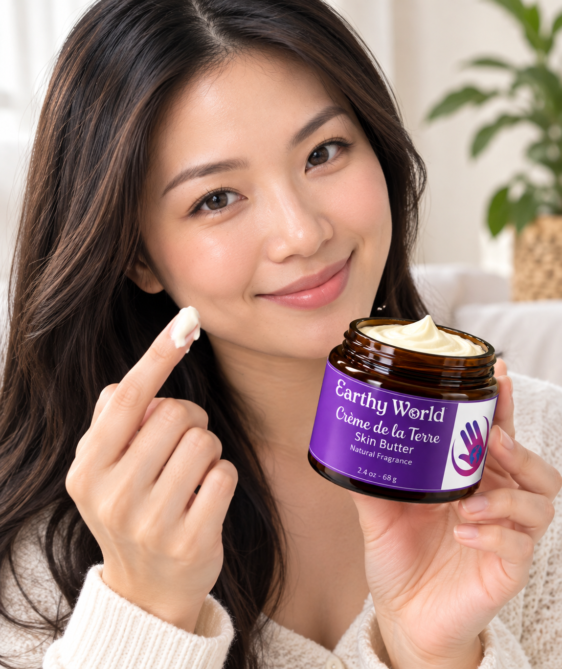 Woman with body butter melting on her finger while holding a container of Creme de la Terre in her other hand