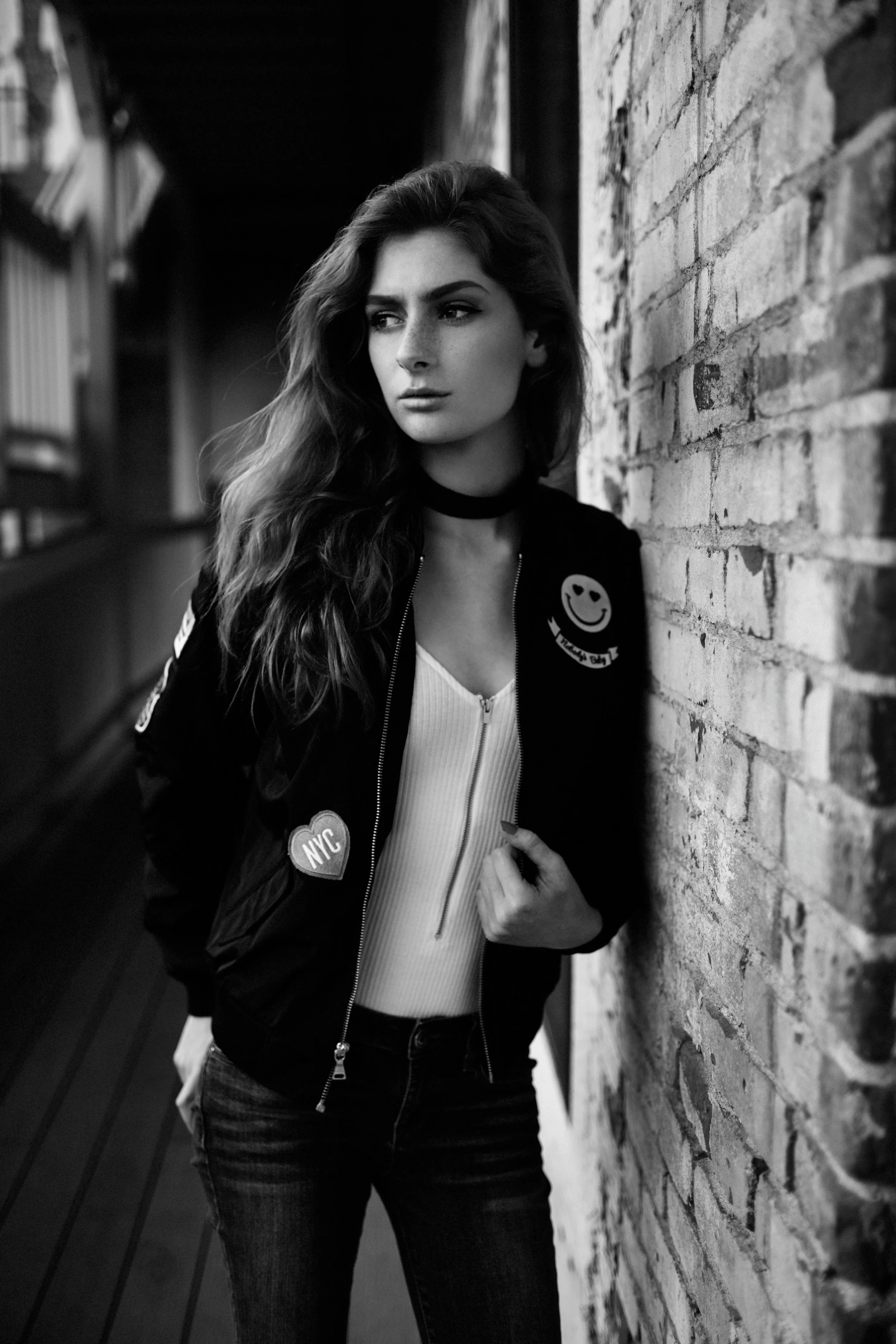 Black-and-white senior portrait of a high school girl photographed against a brick wall in downtown San Luis Obispo, California.