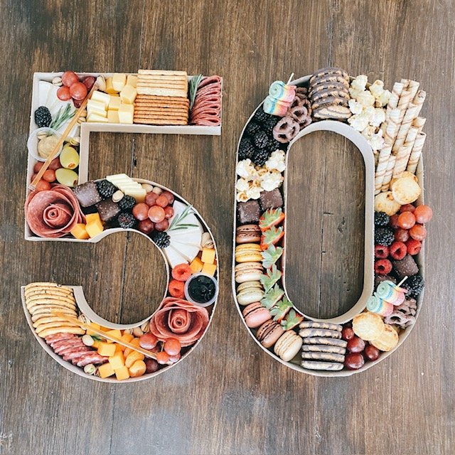 Number 50 made of assorted candies and treats arranged on a wooden surface.