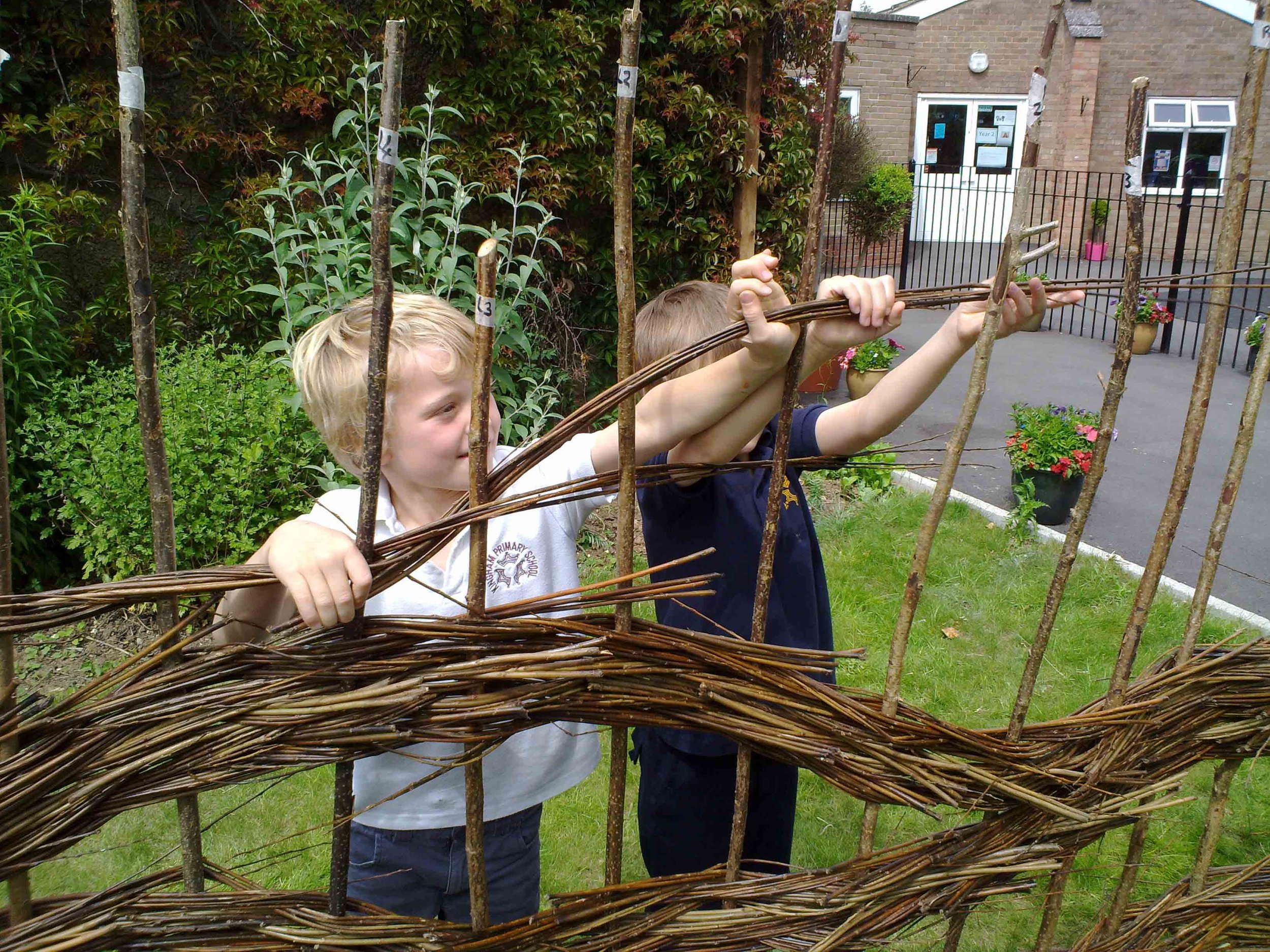 Children making a willow hurdle during a hands-on school art and craft workshop with CreatingART.