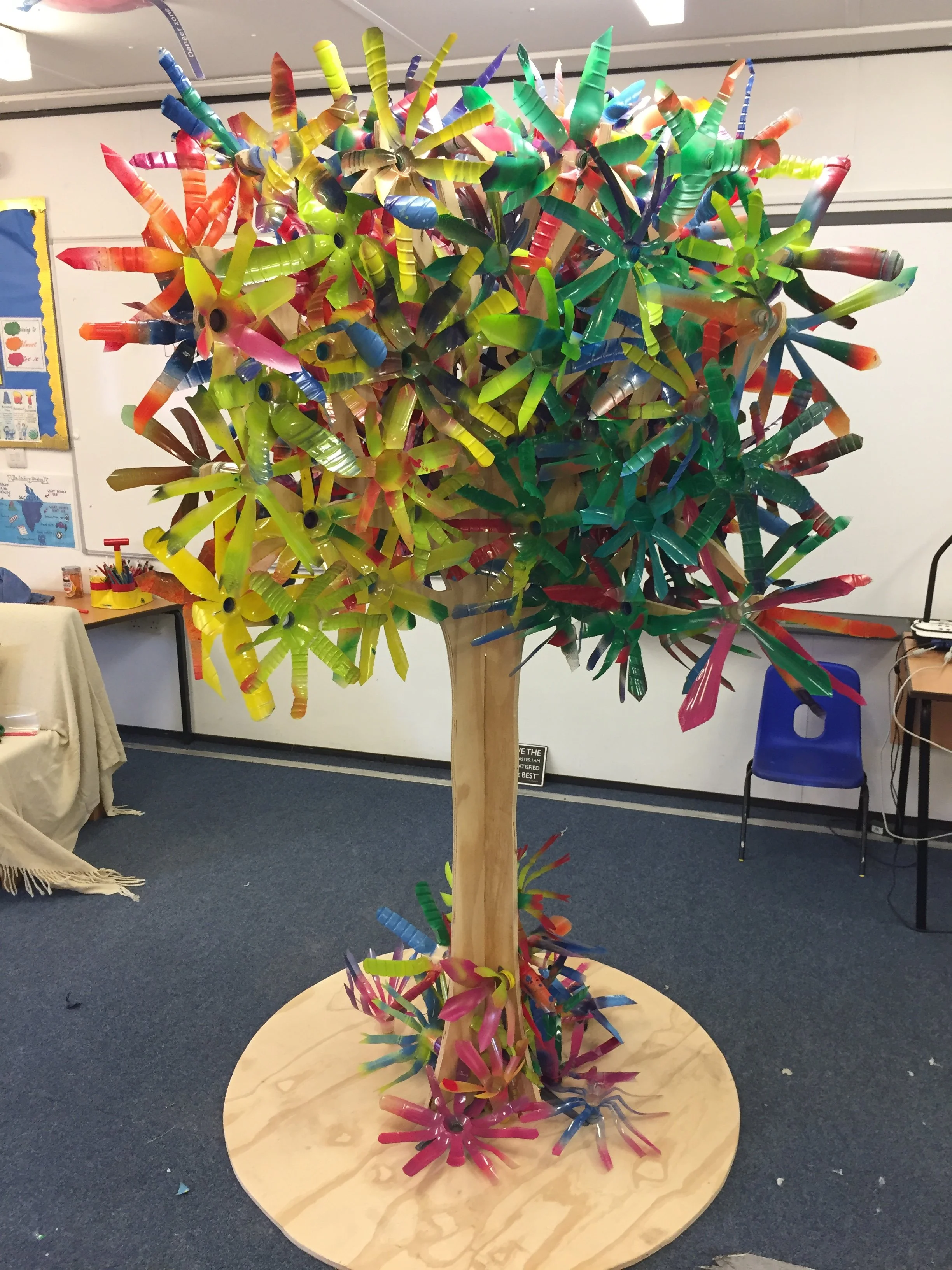 Colorful sculpture of a tree made from plastic and wood in an indoor space.