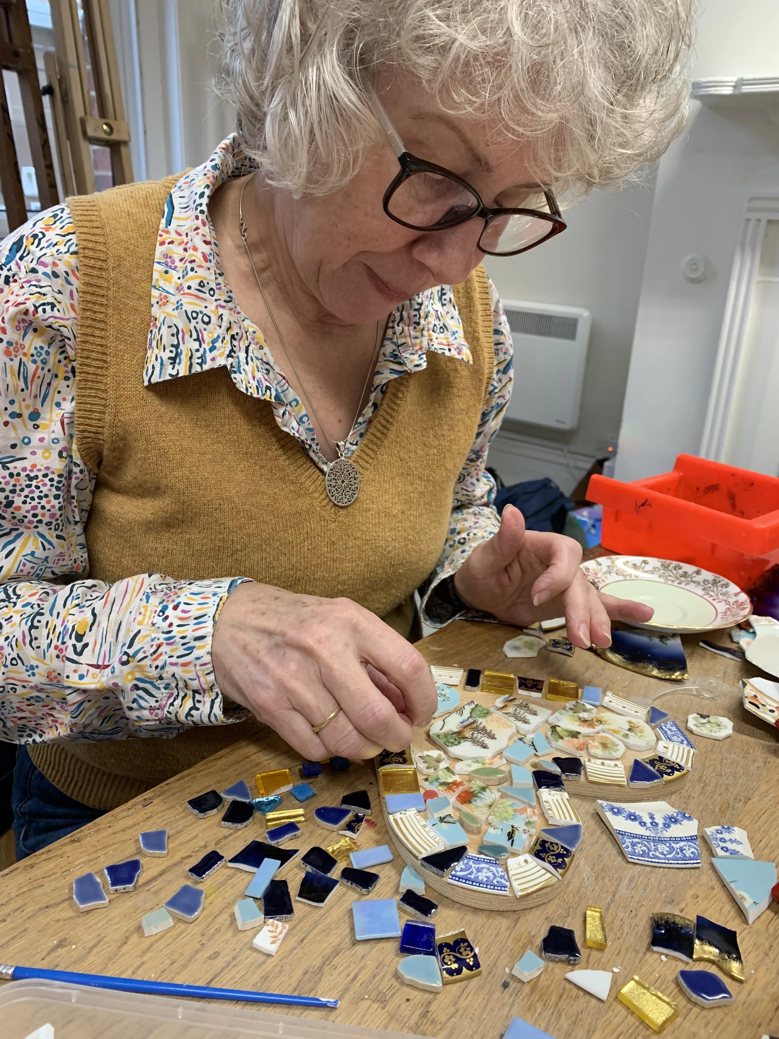 Participant creating a heart from vintage china during an adult mosaic workshop with CreatingART in Wales.