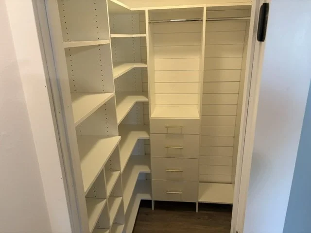Custom white walk-in closet systen with shelves, drawers, and hanging spaces.