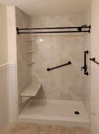 A walk-in shower with three corner shelves, black grab bars, and a black sliding shower curtain rod.