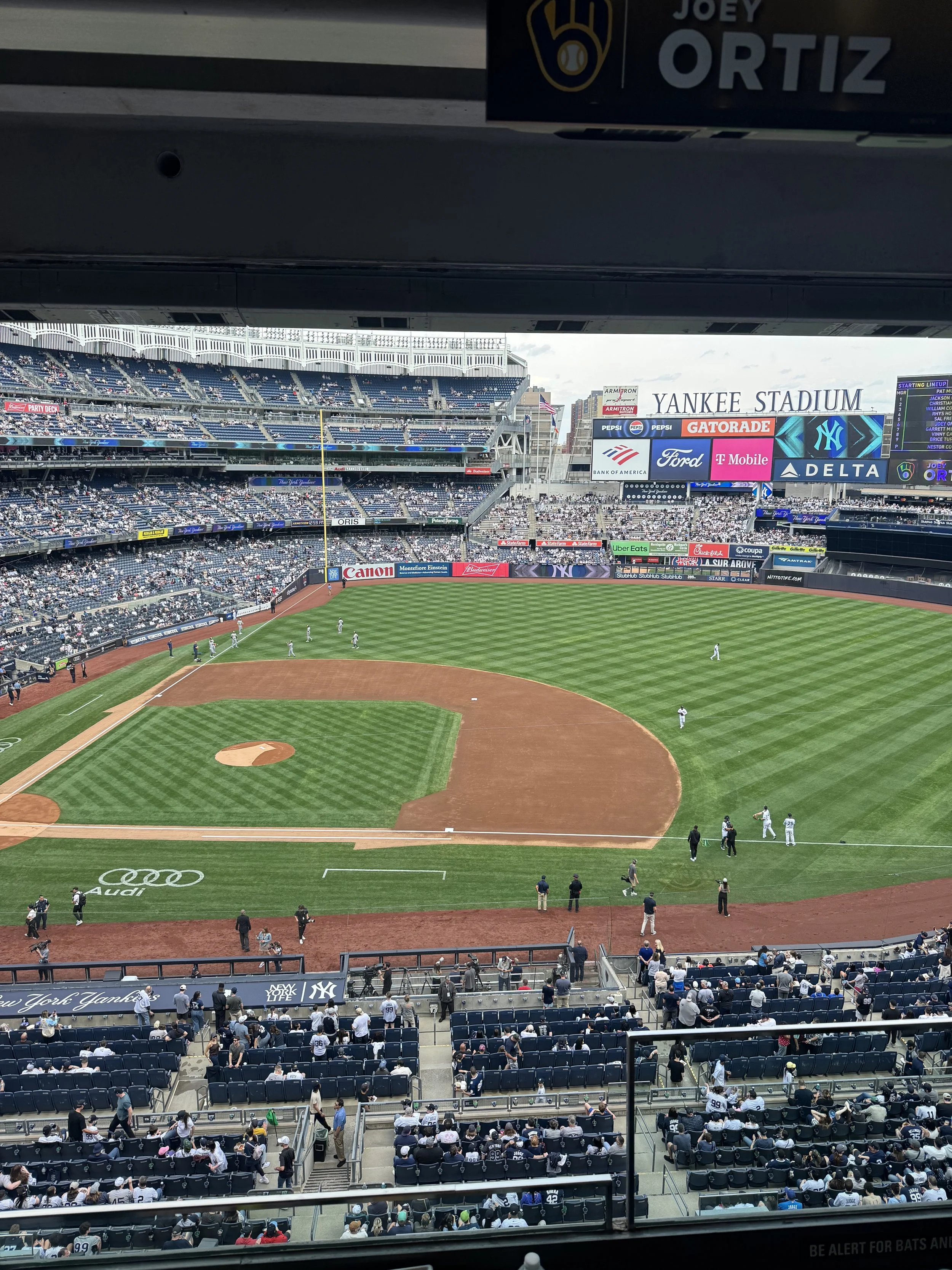 View of Yankee Stadium filled with fans, with players on the field during a baseball game.