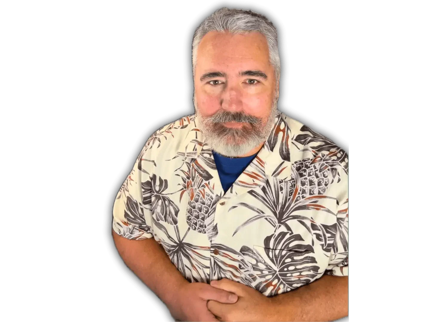 A man with gray hair and a gray beard wearing a floral Hawaiian shirt, standing with arms crossed against a green background.