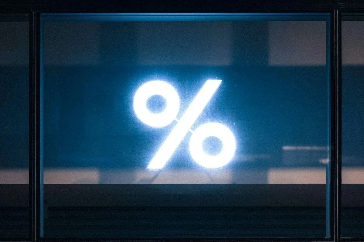Neon light in the shape of a percentage sign on a dark window or screen.