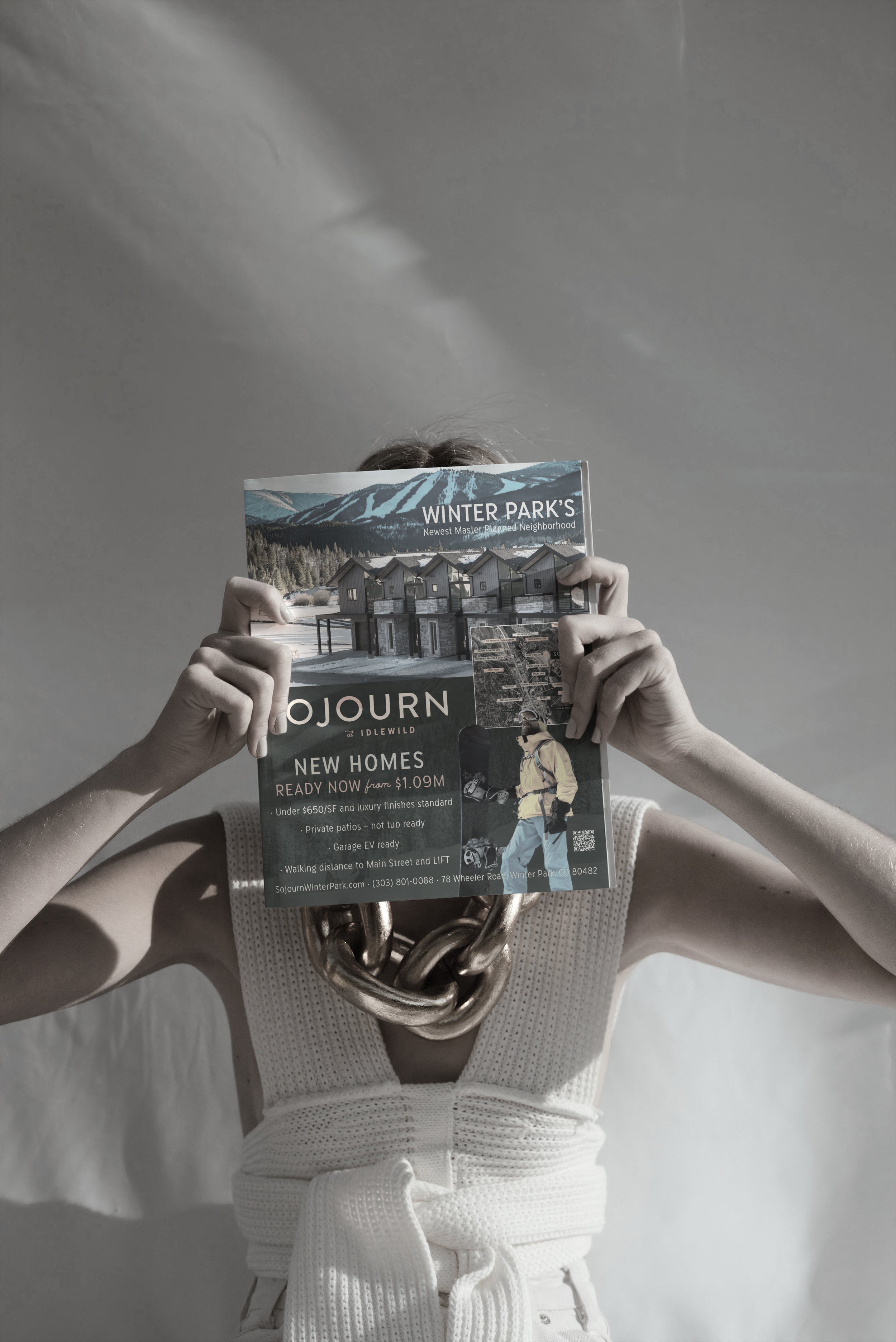 Person dressed in white karate or martial arts uniform, holding a pamphlet for Winter Park new homes, with their face obscured by the pamphlet.