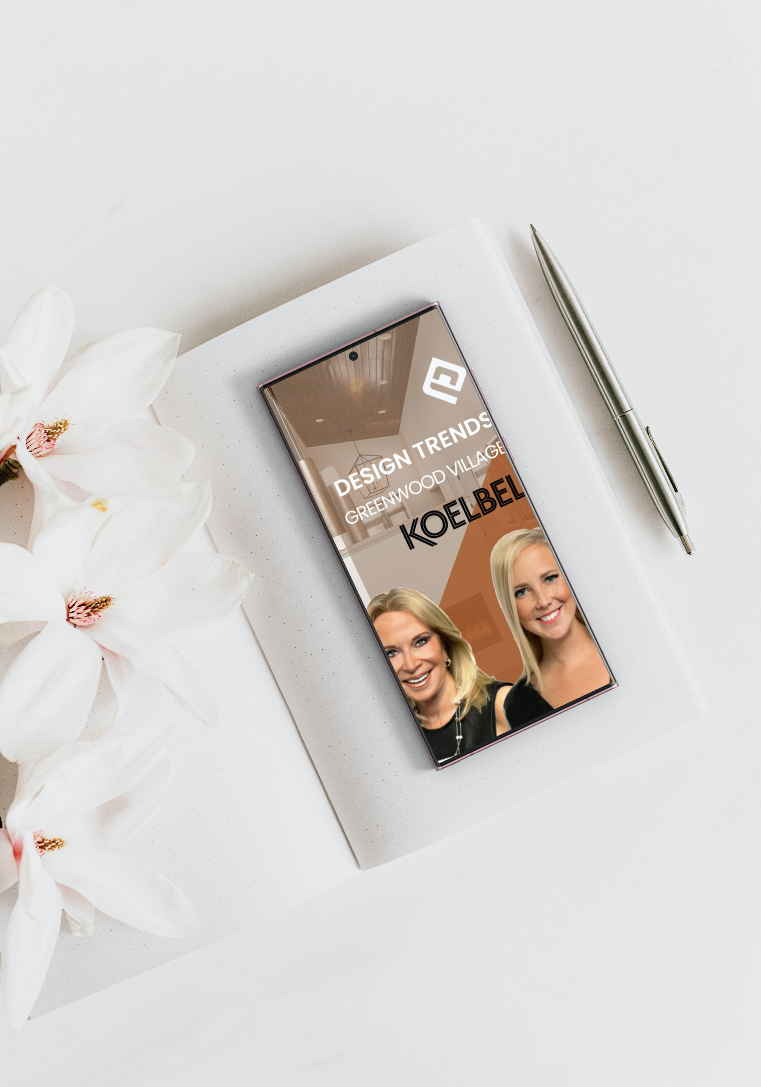 Smartphone on a white notebook with a pen nearby, pink flowers on the left, and a woman smiling on the phone screen, with text about design trends in the background.