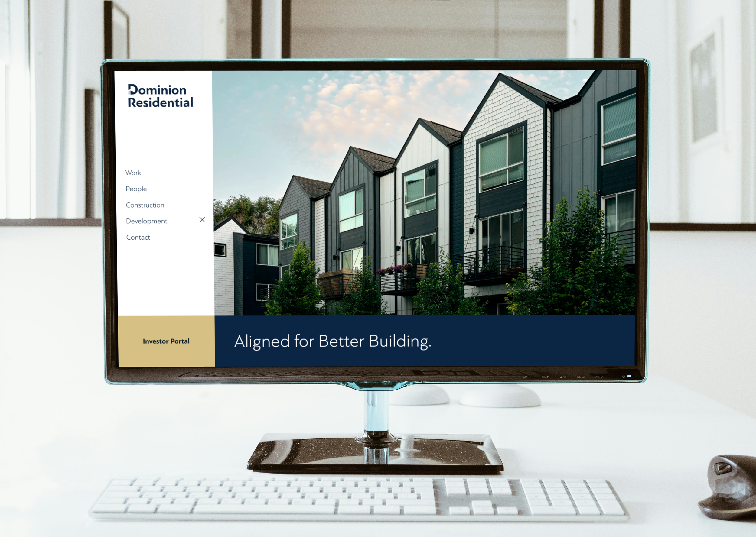 Computer monitor displaying a real estate website with images of modern townhouses, placed on a desk with a keyboard, mouse, and a white background.