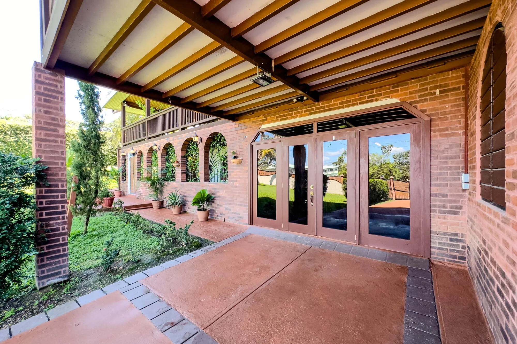 Covered ground-floor verandah at Cayo Mountain View Estate overlooking the landscaped tropical gardens and outdoor areas.