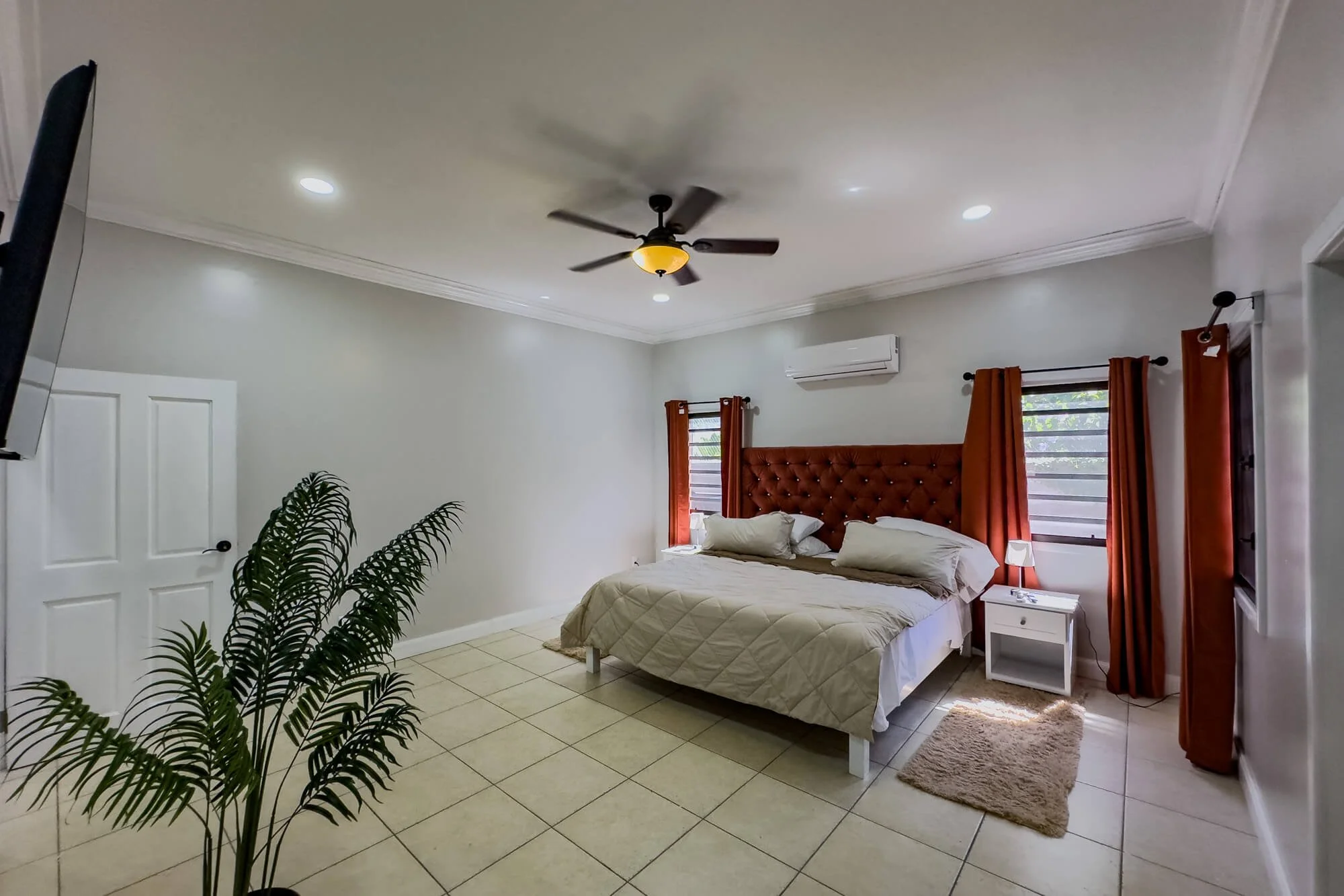 Spacious air-conditioned bedroom at Cayo Mountain View Estate with tiled floors, ceiling fan and abundant natural light.