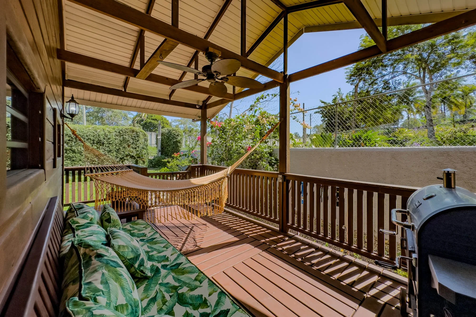 Covered timber verandah with hammock and garden views, providing a relaxed outdoor living area surrounded by tropical greenery.