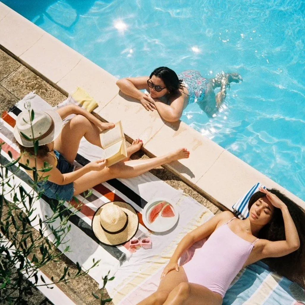 Three women relaxing by pool on vacation together