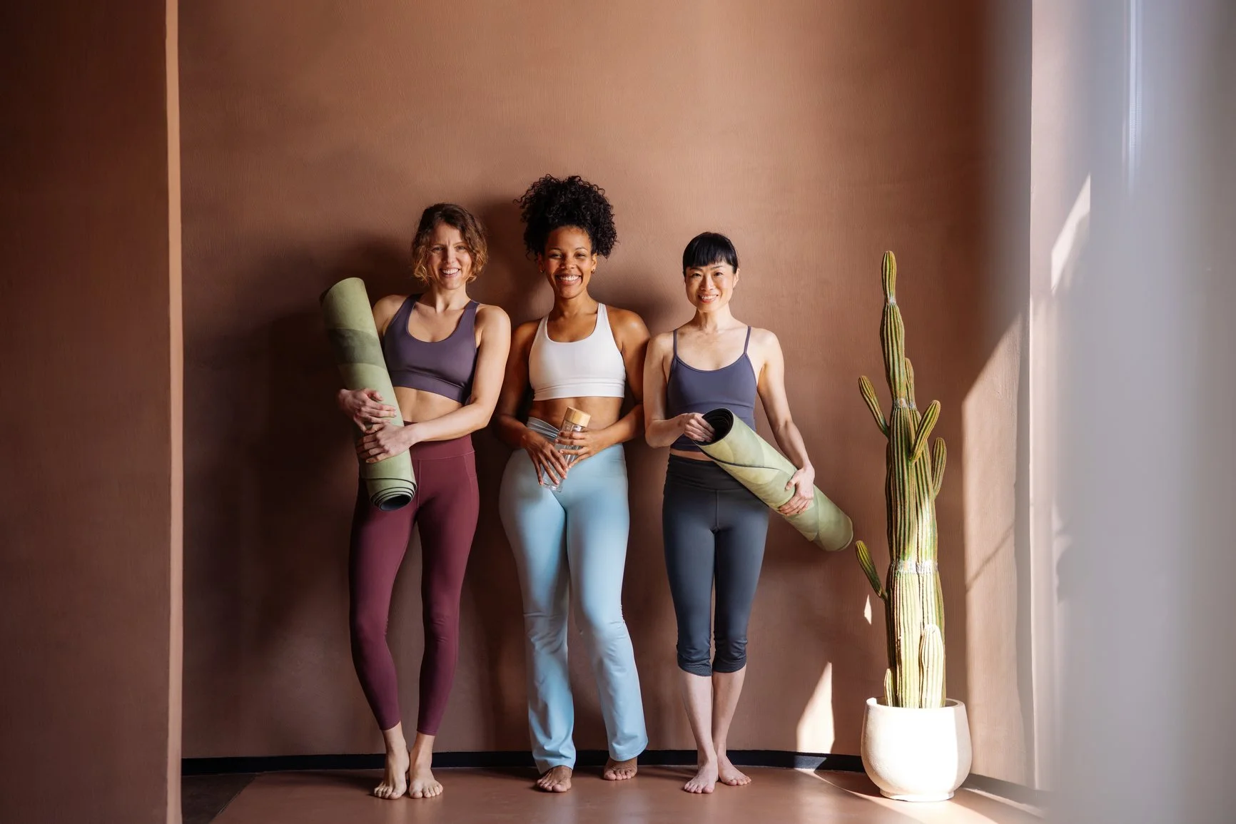 Three women in athletic wear ready for yoga on a women's retreat