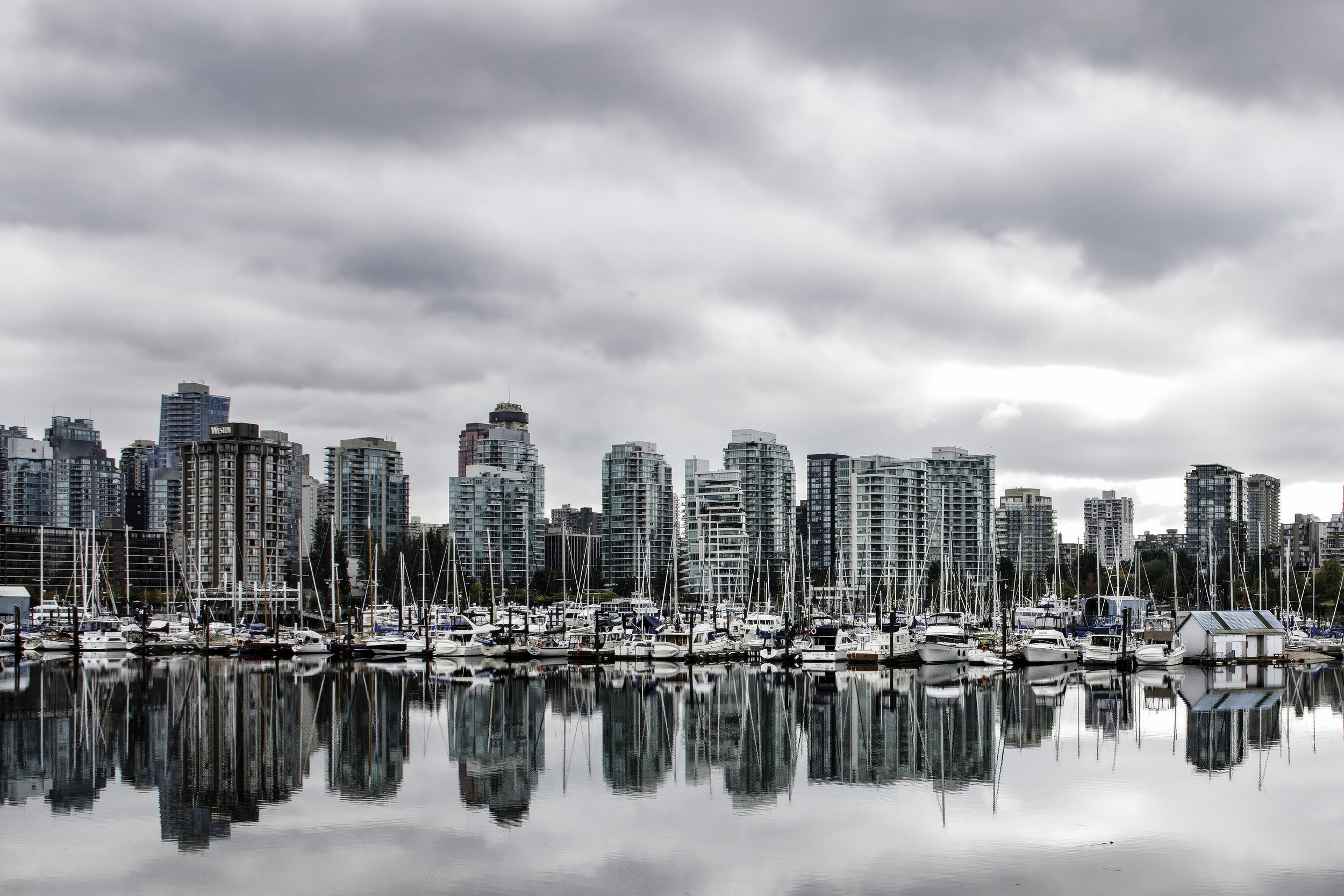 "Vancouver Skyline" - Cloudy skies and calm waters reflect the skyscrapers along the waterfront of downtown Vancouver as seen from Stanley Park.