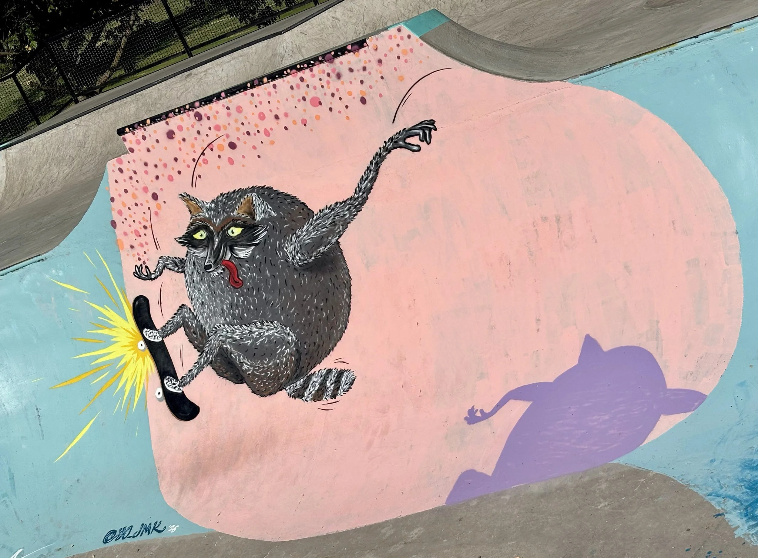 A colorful mural of a cat with yellow eyes, gray fur, and sharp claws holding a large black knife with a yellow burst behind it on a pink and blue background.