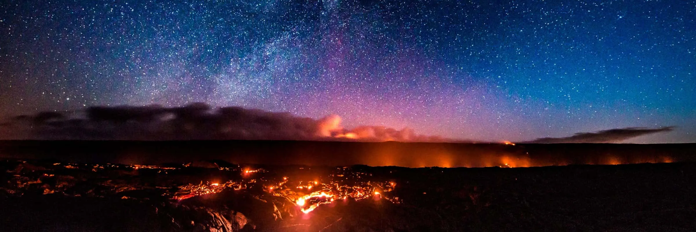 Night sky filled with stars over a landscape with glowing lava and clouds.