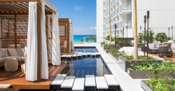 Luxury rooftop pool area with cabanas, lounge chairs, and ocean view