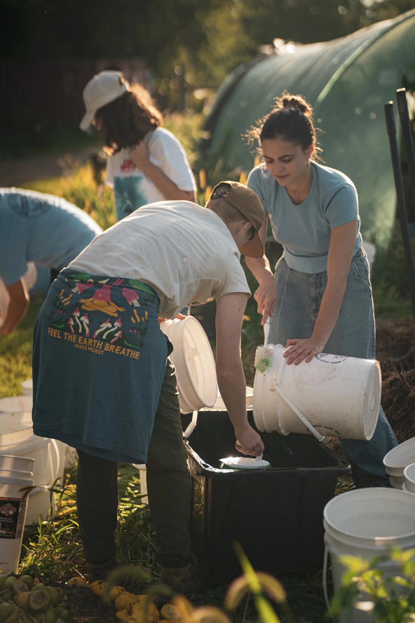 Volunteers wash reusable food-scrap buckets together at Brainplate Grows’ Compost Olympics.