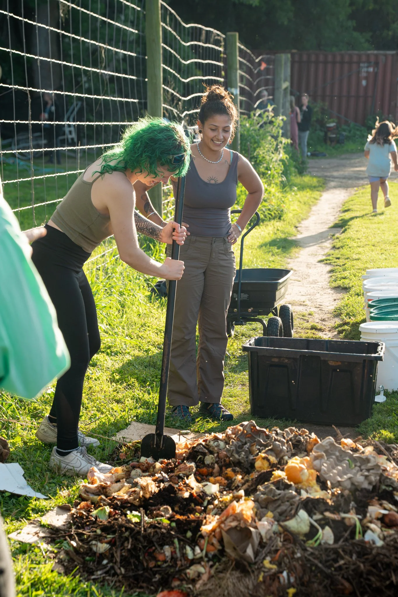 Two volunteers work beside a food-scrap pile during Brainplate Grows’ Compost Olympics.