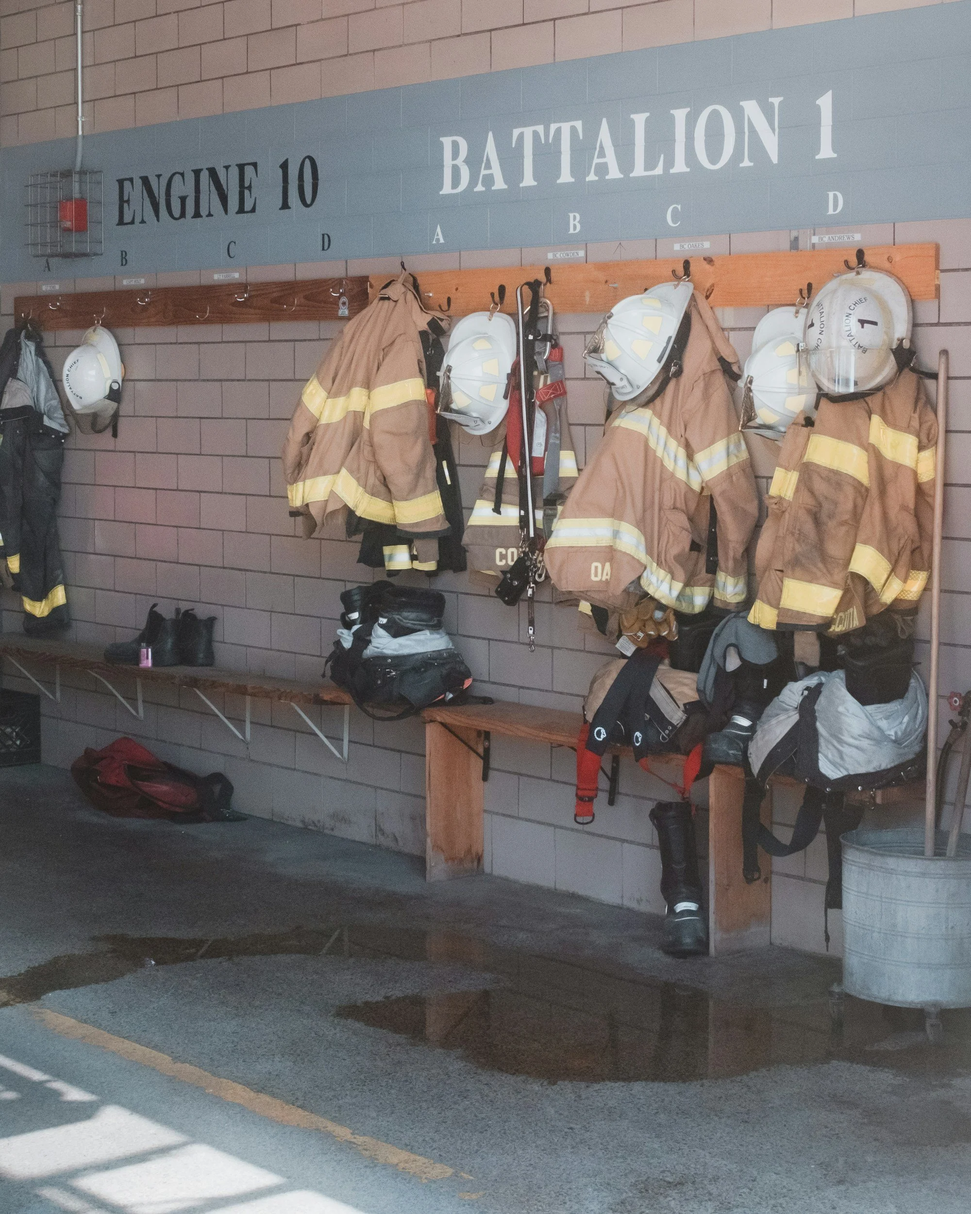 Firefighter turnout gear and helmets hanging inside a fire station.
